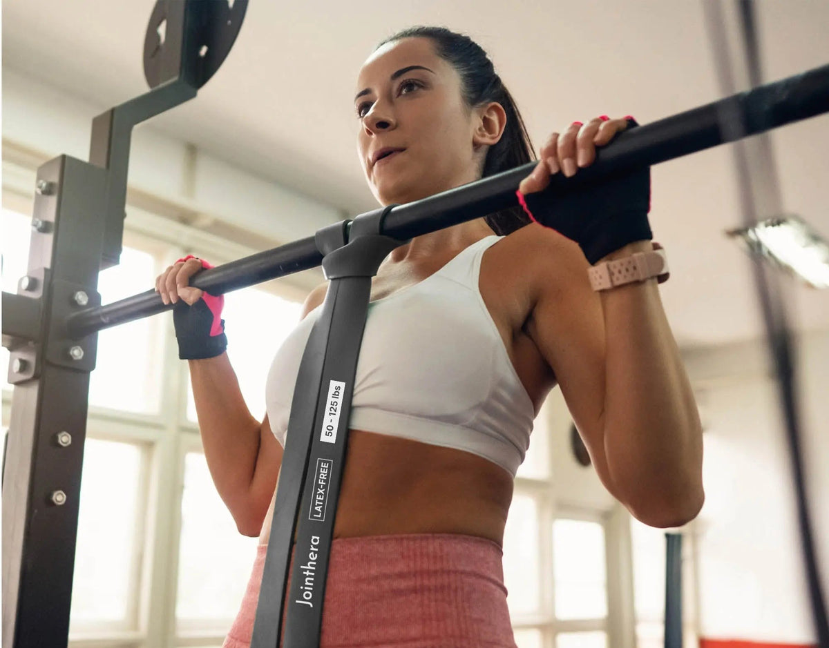 Woman using Jointhera pull up assistance bands at a pull-up bar
